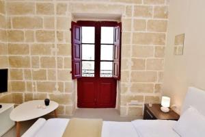 瓦莱塔Lucky Star 402 by Vallettastay的石墙客房内的红色门,配有白色沙发