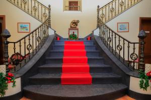 a red carpeted staircase with a red carpetllor at Bella Italia Pópulo Guest House in Ponta Delgada