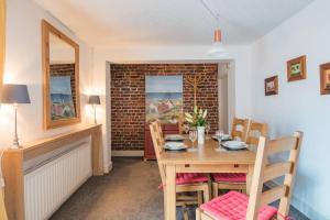 een eetkamer met een tafel en stoelen en een bakstenen muur bij Lighthouse Cottage in Deal
