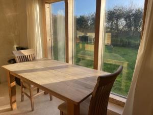 einen Holztisch und Stühle vor einem Fenster in der Unterkunft Shortlake Cottage in Osmington