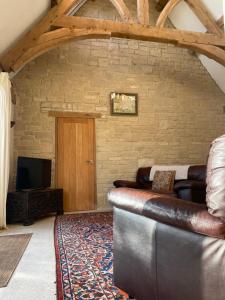 ein Wohnzimmer mit einem Ledersofa und einem TV in der Unterkunft Shortlake Cottage in Osmington