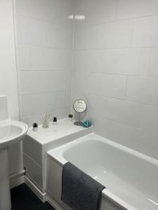 a white bathroom with a bath tub and a sink at Woolfall House in Roby