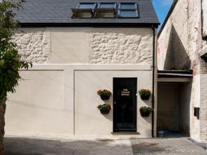 a white garage with a black door and two potted plants at The Coach House in Pembroke Dock