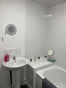 a white bathroom with a sink and a tub at Woolfall House in Roby