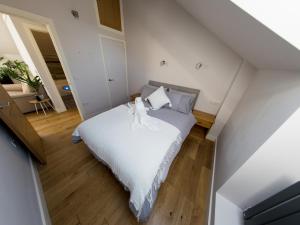 a bedroom with a bed with white sheets and wooden floors at The Coach House in Pembroke Dock