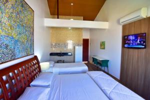 1 dormitorio con 2 camas y TV en la pared en FLAT Estalagem 11, en Arraial do Cabo