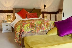 a bedroom with a large bed with colorful blankets and pillows at Samsara in West Peckham