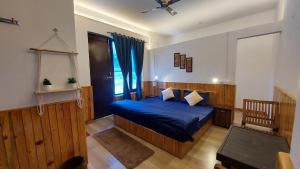 um quarto com uma cama azul e uma janela em The Hostel Stories, Bir - Landing Site em Bir