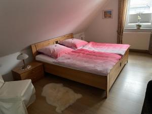 Schlafzimmer mit einem Bett mit rosa Bettwäsche und einem Teppich in der Unterkunft Ferienwohnung Wilzenbergblick in Schmallenberg