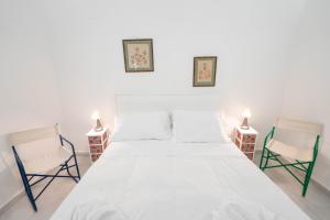 um quarto com uma grande cama branca e 2 cadeiras em Vico Amico by Dimorra em Nápoles