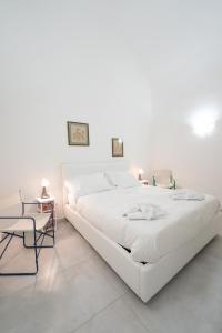 um quarto branco com uma grande cama branca e uma cadeira em Vico Amico by Dimorra em Nápoles