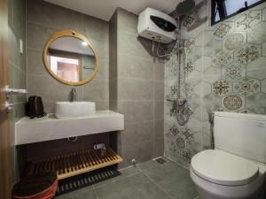 ein Badezimmer mit einem WC, einem Waschbecken und einem Spiegel in der Unterkunft Wings House in Đà Nẵng