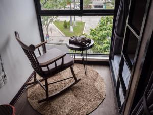 einen Schaukelstuhl und einen Tisch vor einem Fenster in der Unterkunft Wings House in Đà Nẵng