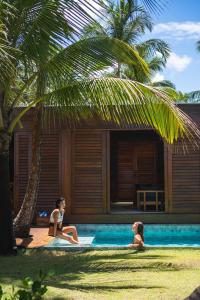 Dos mujeres sentadas en una piscina al lado de una casa en Villa Kandui Boutique Hotel e Beach Lounge en Barra Grande