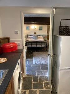a kitchen with a refrigerator and a room with a bed at Mill Retreat at Bissick Old Mill in Truro