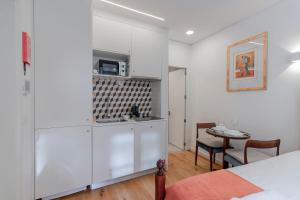 eine Küche mit weißen Schränken und einem Tisch im Zimmer in der Unterkunft Cozy Studio w/ Patio by LovelyStay in Porto