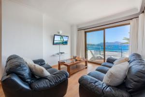 a living room with a leather couch and a large window at Anita Apartments in Port de Pollensa