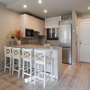 a kitchen with a white island and white stools at Tanau by FeelFree Rentals in Naut Aran