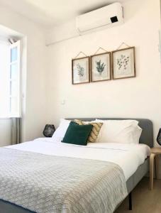 een slaapkamer met een wit bed en drie foto's aan de muur bij Sinos da Sé in Setúbal