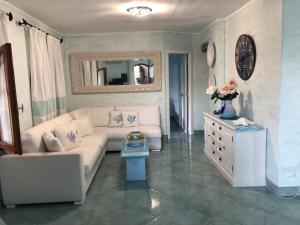un soggiorno con divano bianco e specchio di Appartamento in villa Porto Istana a Olbia