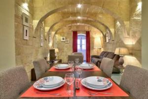 uma sala de jantar com uma mesa com pratos e copos de vinho em VALLETTASTAY - ORANGERIE TWO BEDROOM APARTMENT 201 em Valletta