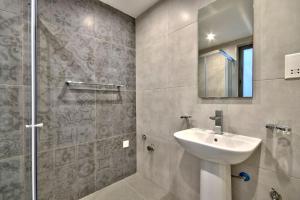 uma casa de banho com um lavatório e um chuveiro em VALLETTASTAY - ORANGERIE TWO BEDROOM APARTMENT 201 em Valeta