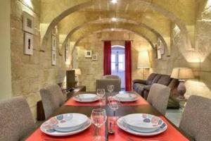 uma sala de jantar com uma mesa com pratos e copos de vinho em VALLETTASTAY - ORANGERIE TWO BEDROOM APARTMENT 201 em Valletta