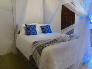 ein Schlafzimmer mit einem weißen Bett mit blauen Kissen in der Unterkunft Moz T's Lodge in Inhambane