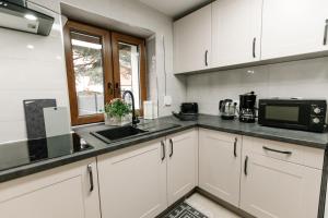 a kitchen with white cabinets and a sink and a microwave at Apartament KARO 1 Karkonosze in Jelenia Góra