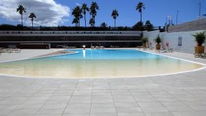 uma grande piscina num edifício com palmeiras em Timeless clock Apartment em San Bartolomé