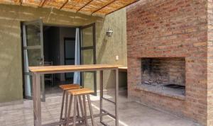 a brick fireplace in a patio with a table and stools at Complejo Turístico Chachingo in Maipú