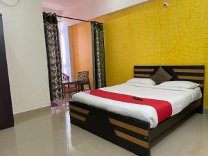 a bedroom with a large bed with a yellow wall at Green Valley Residency in Gundlupet