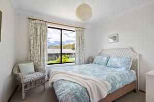 a bedroom with a bed and a window and a chair at Kelton Beach Haven in Mollymook