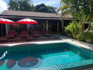 a swimming pool with chairs and umbrellas next to a house at Veni Vana Valley Maetang in Ban Chang