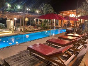 a swimming pool with tables and umbrellas next to a pool at Veni Vana Valley in Ban Chang