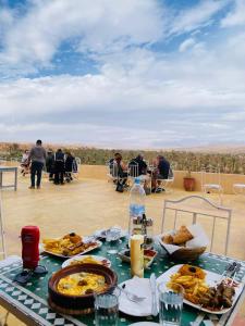 a table with food on top of a roof at Hotel Kasbah Ennakhile - Authentic Stay in Nkob in Nkob