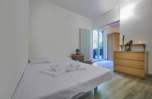 a bedroom with a white bed and a wooden dresser at Nicola Flat in Lierna