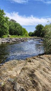 a river with rocks and trees on the side at Chalets de la paix in Santa Rosa de Calamuchita