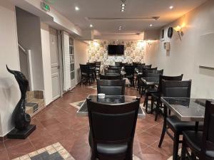 a restaurant with black chairs and tables and a television at Hôtel de l'Aveyron in Paris