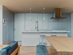 eine Küche mit einem Holztisch und einem blauen Sofa in der Unterkunft Playliving IZU - A ocean view villa with Onsen in Ito