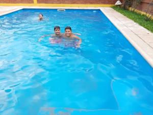 Dos personas nadando en una piscina azul en LOS BULGAROS en Villa Cura Brochero