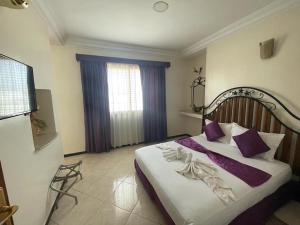 a bedroom with a large bed with purple pillows at Perla Hôtel in Fès