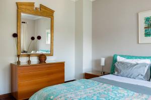 a bedroom with a bed with a dresser and a mirror at Traditional Villa In S Pedro , ESTORIL in Alapraia