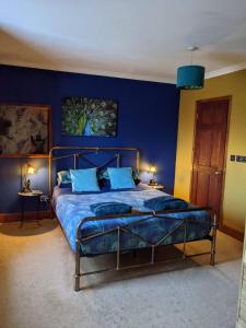 1 dormitorio con 1 cama con pared azul en Hideaway Escapes, Farmhouse B&B & Holiday Home, Ideal family stay or Romantic break, Friendly animals on our smallholding in beautiful Pembrokeshire setting close to Narberth, en Narberth