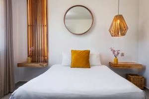 a white bed with a yellow pillow and a mirror at Balkon Boutique Hotel in Playa del Carmen