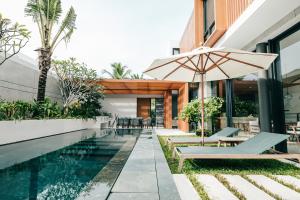 a pool with an umbrella next to a building at Joy Villa in Sailing Club Phu Quoc - 3BR with private pool in Phu Quoc