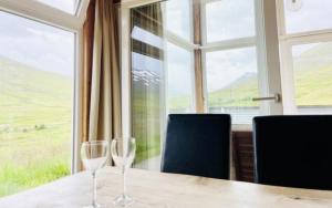 two wine glasses sitting on a table in front of a window at Hidden Cottages 