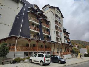 a large building with a car parked in front of it at Suncani apartman 36, Brzece in Brzeće