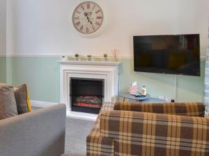 a living room with a fireplace and a clock on the wall at Bramble Cottage in Brampton