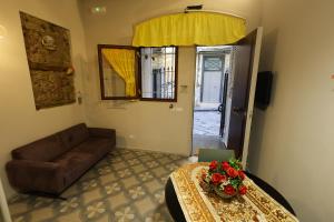 ein Wohnzimmer mit einem Sofa und einem Tisch mit Blumen darauf in der Unterkunft IL BASSO ACCOMODATION in Neapel